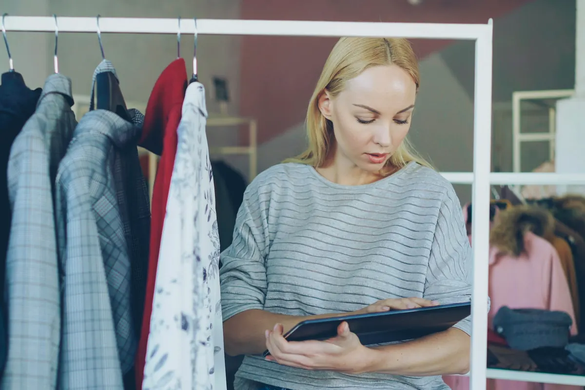 Une commerçante consulte une tablette pour gérer son stock de vêtements
